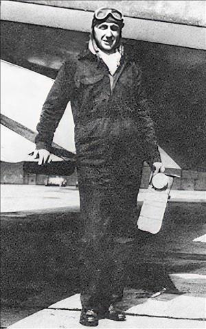 A man in a flight suit holding a lamp and standing in front of a plane